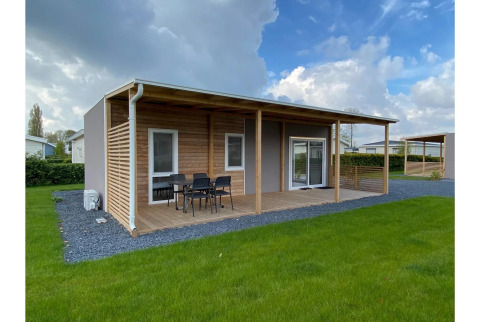 Cabaña moderna Cottage 4 con terraza techada y césped verde en De Biesbosch, Países Bajos.