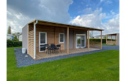 Cabaña moderna Cottage 4 con terraza techada y césped verde en De Biesbosch, Países Bajos.