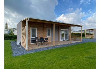 Cabaña moderna Cottage 4 con terraza techada y césped verde en De Biesbosch, Países Bajos.