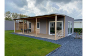 Foto der Cottage 4 Lodge im De Biesbosch in den Niederlanden mit moderner Terrasse und gepflegtem Rasen.