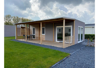 Foto del Lodge Cottage 4 en De Biesbosch, Países Bajos, con terraza de madera y césped verde al aire libre.