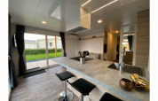 Modern lodge Cottage 4 bij De Biesbosch in Nederland, met keukeneiland, barkrukken en tuinzicht.