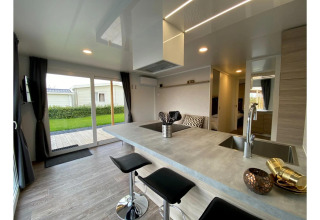 Moderne lodge Cottage 4 ved De Biesbosch i Holland, med køkkenø, barstole og udsigt til haven.