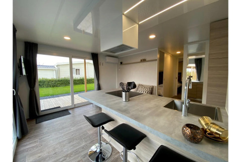 Lodge moderne Cottage 4 à De Biesbosch, Pays-Bas, avec îlot de cuisine, tabourets et vue sur le jardin.