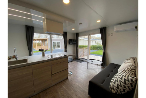 Sala de estar y cocina modernas en Cottage 4 de De Biesbosch, Países Bajos, con ventanas grandes y decoración elegante.