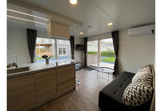 Moderne stue og køkken i Cottage 4 på De Biesbosch, Holland, med store vinduer og stilfuld indretning.