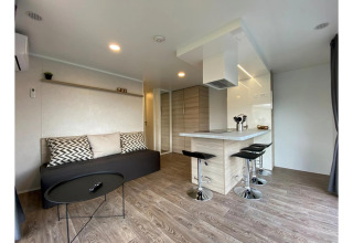 Moderne stue og køkken i Cottage 4 på De Biesbosch, Holland, med minimalistisk indretning og barstole.