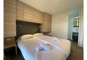 Dormitorio moderno con cama doble, sábanas limpias, toallas y armarios de madera en Cottage 4, De Biesbosch.