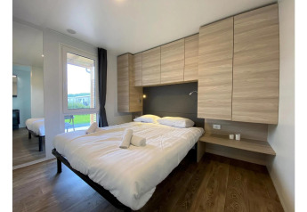 Moderne slaapkamer in Cottage 4 in De Biesbosch, Nederland, met tweepersoonsbed en houten kasten.