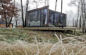 Cabaña moderna de cristal llamada Cabin on the Hill en Wilsumer Berge, Alemania, rodeada de árboles helados.