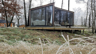 Moderne glasbeklædt hytte kaldet Cabin on the Hill ved Wilsumer Berge, omgivet af frostklædte træer.