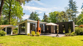 Moderne L-Pavilion 6 lodge in De Biesbosch in Nederland met terras, parasol en groene omgeving.