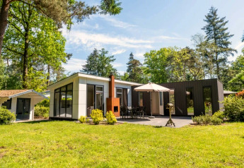 Moderno lodge L-Pavilion 6 en De Biesbosch, Países Bajos, con terraza, sombrilla y zona verde.
