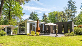 Modern L-Pavilion 6 lodge at De Biesbosch in the Netherlands with patio, umbrella, and lush greenery.