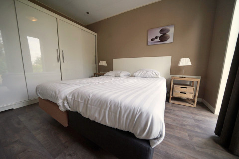 Modern bedroom at L-Pavilion 6 in De Biesbosch, Netherlands, featuring a double bed and minimalist decor.