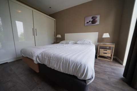 Camera moderna al L-Pavilion 6 a De Biesbosch, Paesi Bassi, con letto doppio e decorazione minimalista.