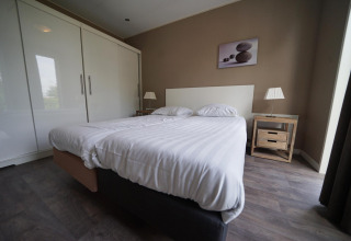 Dormitorio moderno en L-Pavilion 6 en De Biesbosch, Países Bajos, con cama doble y decoración minimalista.