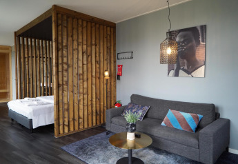 Moderne lodge med trægitter, grå sofa, farverige puder og vægkunst i Mode Wellness 2, Marina Strandbad, Holland.
