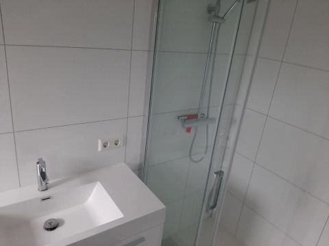 Bagno moderno con lavabo bianco, doccia e piastrelle bianche presso Mode Wellness 2 al Marina Strandbad, Paesi Bassi.