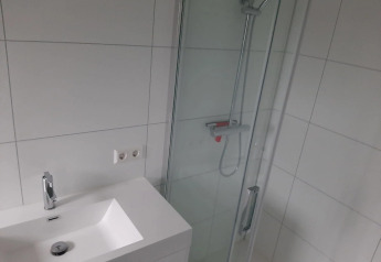 Moderne badeværelse med hvid vask, spejl, bruser og hvide fliser i Mode Wellness 2 på Marina Strandbad.