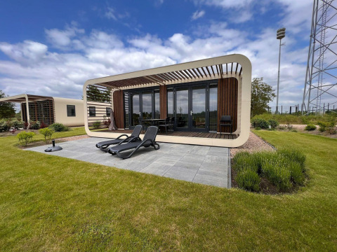 Lodge moderno Mode Wellness 2 en Marina Strandbad, Países Bajos, con terraza, césped y tumbonas negras.