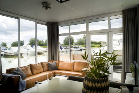 Sala de estar con grandes ventanales y vista a los barcos de la marina en Water lodge 4, Marina Strandbad, Países Bajos.