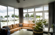 Living room with large windows overlooking boats at the marina in Water lodge 4, Marina Strandbad, Netherlands.