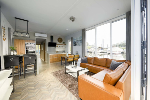 Modernes Wohnzimmer auf dem Hausboot Water Lodge 4 bei Marina Strandbad, Niederlande, mit Ledersofa.
