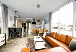 Modern interieur op woonboot Water lodge 4 in Marina Strandbad, Nederland, met grote ramen en lederen zetel.