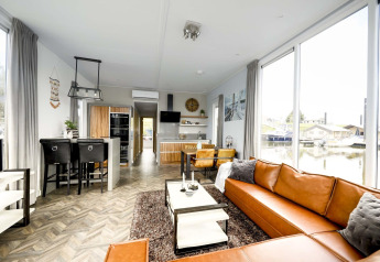 Moderne woonruimte op woonboot, Water lodge 4 bij Marina Strandbad, Nederland, met grote ramen en leren bank.