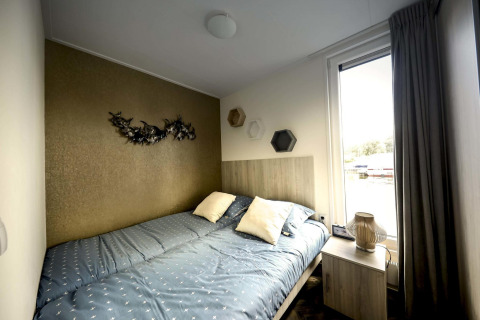 Schlafzimmer mit Doppelbett, moderner Wanddeko und großem Fenster auf einem Hausboot in Marina Strandbad, Niederlande.