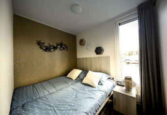 Slaapkamer met tweepersoonsbed, moderne decoratie en groot raam op een woonboot bij Marina Strandbad, Nederland.