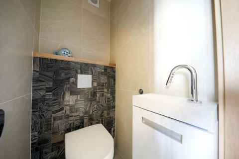 Modern toilet and sink on houseboat Water Lodge 4 at Marina Strandbad, Netherlands, with stylish tiles.