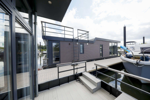 Moderna casa flotante Water Lodge 4 en Marina Strandbad, Países Bajos, con terraza, escalones y barcos atracados.