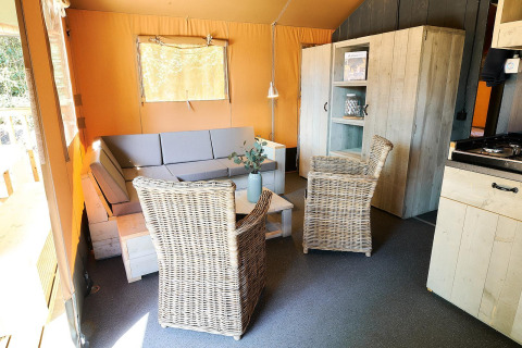 Indvendigt billede af Safari telt ved Wilsumer Berge i Tyskland med sofa, stole og træskabe.