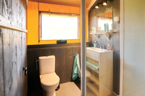 Baño en tienda safari en Wilsumer Berge, Alemania, con inodoro, lavabo, espejo y luz natural.