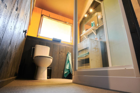 Vista a nivel del suelo de un baño moderno en la tienda Safari de Wilsumer Berge, Alemania, con inodoro y ducha.