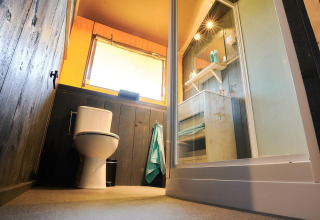 Vista a nivel del suelo de un baño moderno en la tienda Safari de Wilsumer Berge, Alemania, con inodoro y ducha.