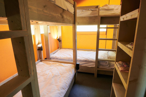 Interno di una tenda Safari al Wilsumer Berge in Germania, con letti a castello e scaffali in legno.