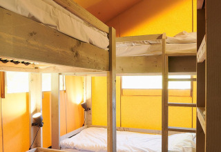 Vue intérieure d'une tente Safari à Wilsumer Berge, Allemagne, avec quatre lits superposés et murs jaunes.