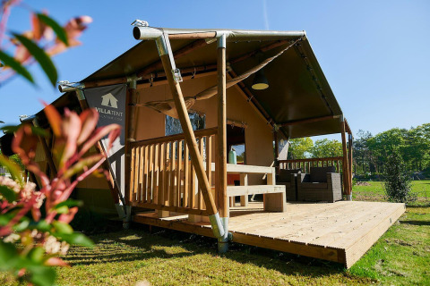 Tienda safari con terraza de madera en el lodge Wilsumer Berge en Alemania durante un día soleado.