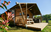 Tienda safari con terraza de madera en el lodge Wilsumer Berge en Alemania durante un día soleado.