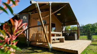 Safaritent met houten terras bij de Wilsumer Berge lodge in Duitsland op een zonnige dag, vooraanzicht.