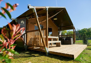 Tienda safari con terraza de madera en el lodge Wilsumer Berge en Alemania durante un día soleado.
