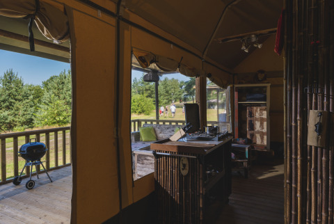 Vista interior de una tienda safari en Wilsumer Berge, Alemania, con terraza, parrilla y espacio natural.