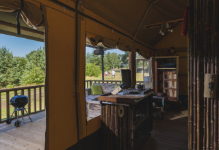 Vista interior de una tienda safari en Wilsumer Berge, Alemania, con terraza, parrilla y espacio natural.