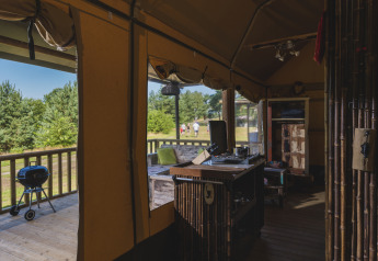 Vista interior de una tienda safari en Wilsumer Berge, Alemania, con terraza, parrilla y espacio natural.