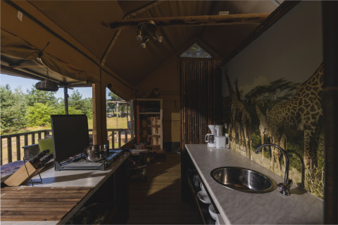Cocina dentro de una tienda safari en Wilsumer Berge, Alemania, con mural de jirafas y electrodomésticos.