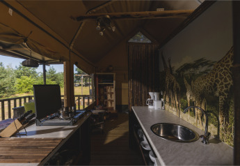 Cocina dentro de una tienda safari en Wilsumer Berge, Alemania, con mural de jirafas y electrodomésticos.