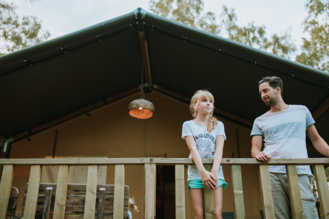 Un uomo e una ragazza sono sul balcone di una tenda safari a Wilsumer Berge in Germania.